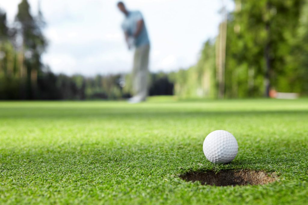 A golf ball in a hole on a golf course.